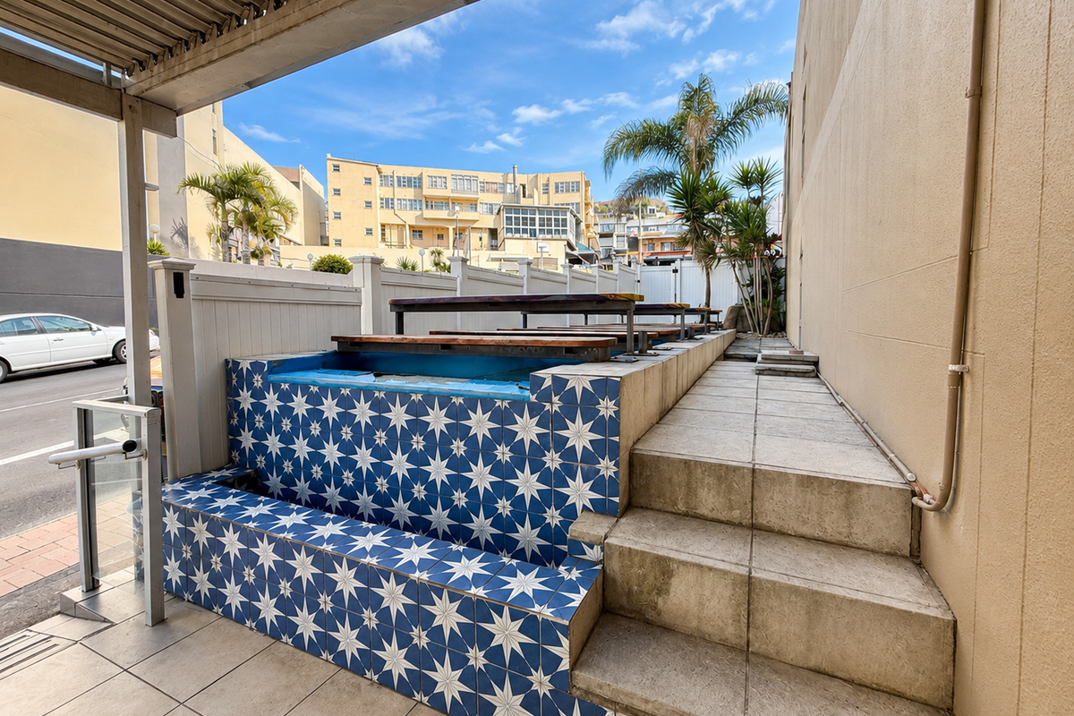 Outdoor patio area featuring a decorative tiled retaining wall, staircase access, and a covered pergola structure.