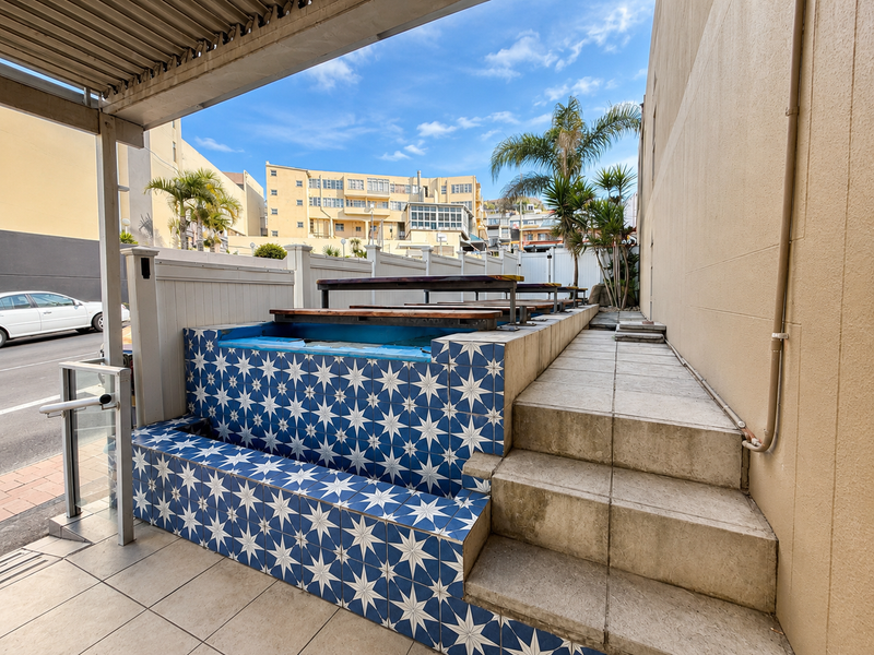 Outdoor patio area featuring a decorative tiled retaining wall, staircase access, and a covered pergola structure.