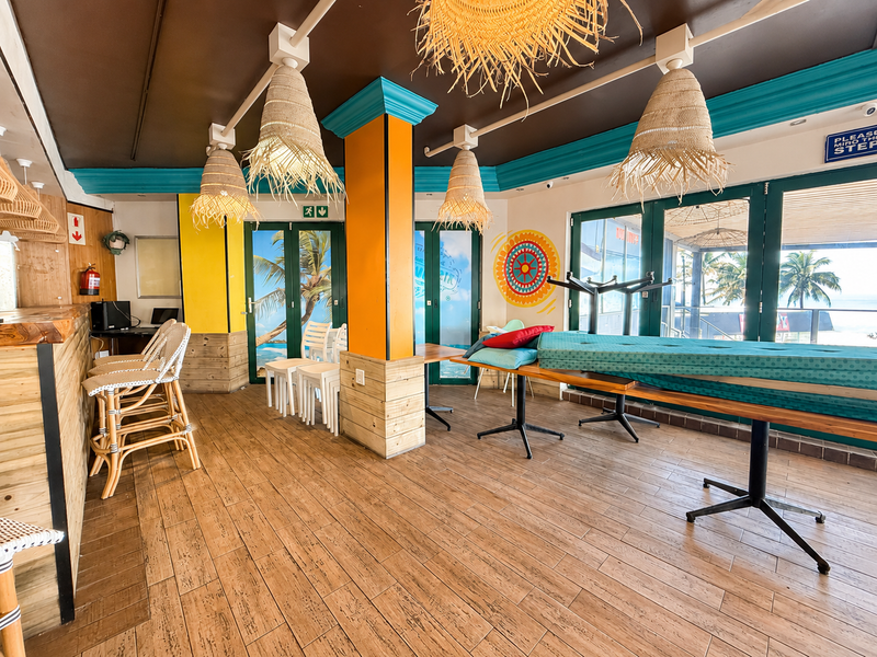 A vibrant restaurant bar area featuring timber-look tiled flooring, a built-in bar counter, and bi-fold glass doors opening to an outdoor view.