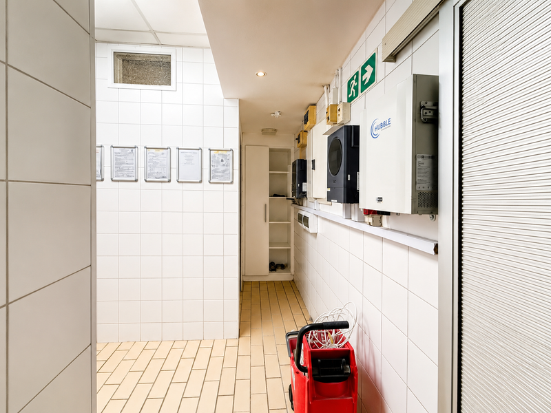 A clean and functional utility space featuring tiled surfaces, built-in storage, and wall-mounted electrical infrastructure including an inverter system.