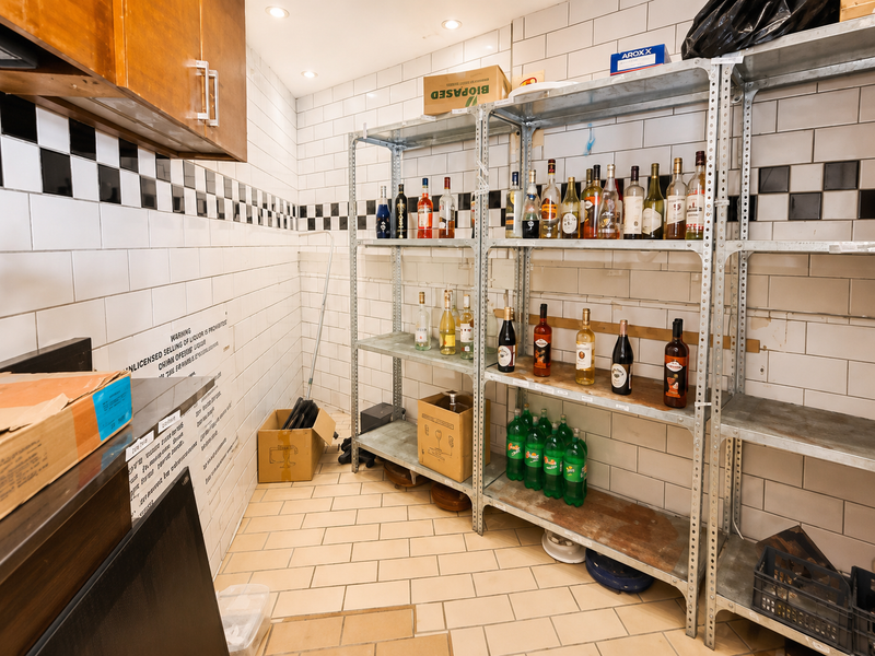 A functional storage and prep area featuring subway tile walls, recessed lighting, and industrial metal shelving units for organized inventory storage.