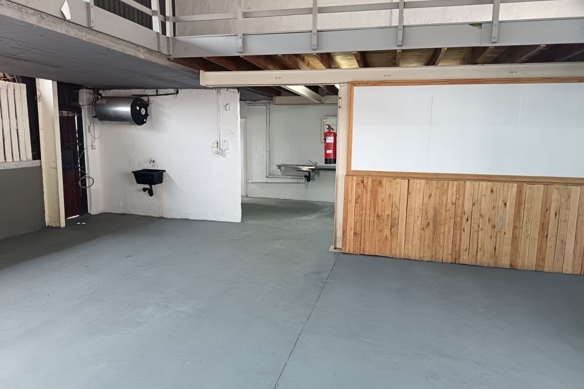Industrial utility space featuring a mezzanine level, dual sink areas, and functional wall-mounted fixtures, suitable for workshop or storage use.
