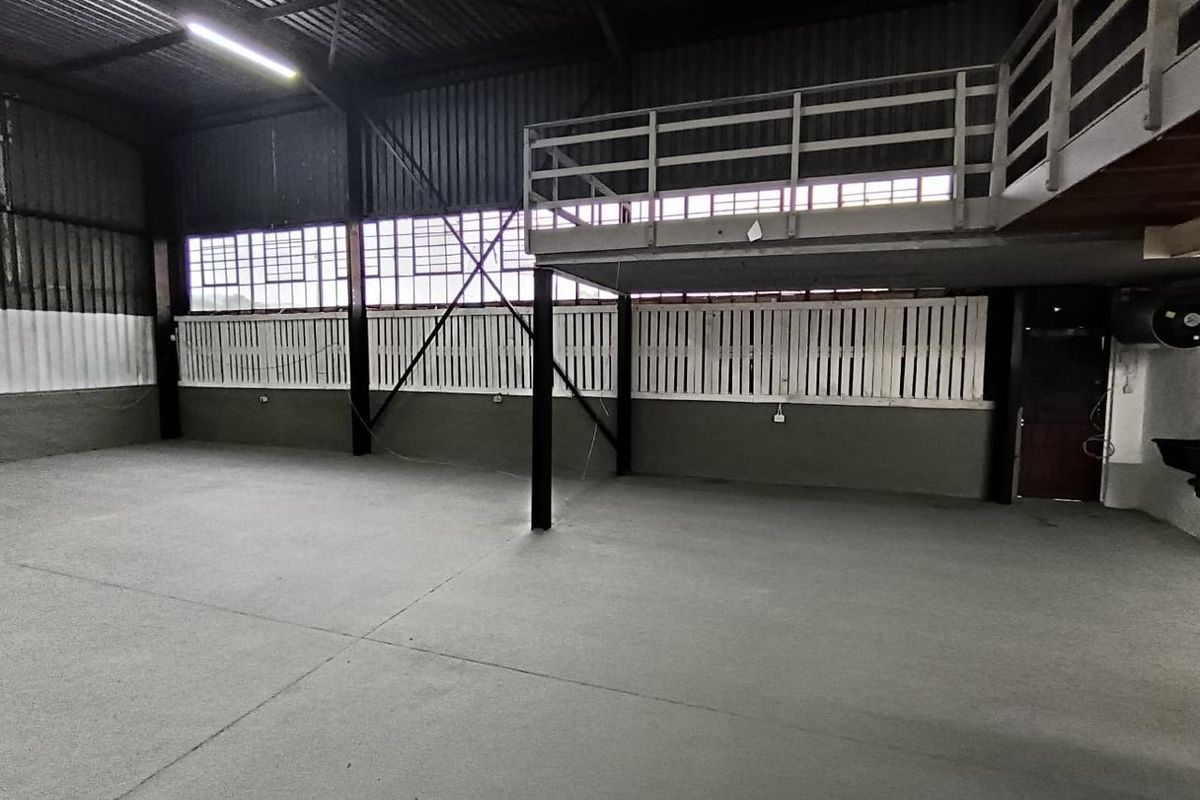 Spacious industrial utility area featuring high ceilings, concrete flooring, and a mezzanine level, suitable for storage, workshop, or versatile commercial use.