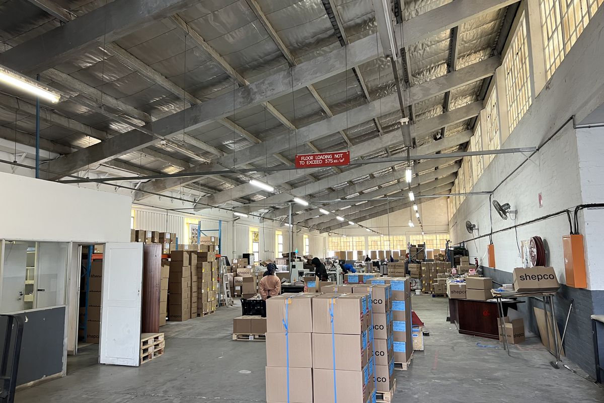 Spacious industrial warehouse facility featuring high-clearance ceilings with exposed steel trusses, concrete flooring, and functional overhead lighting suitable for storage or manufacturing operations.