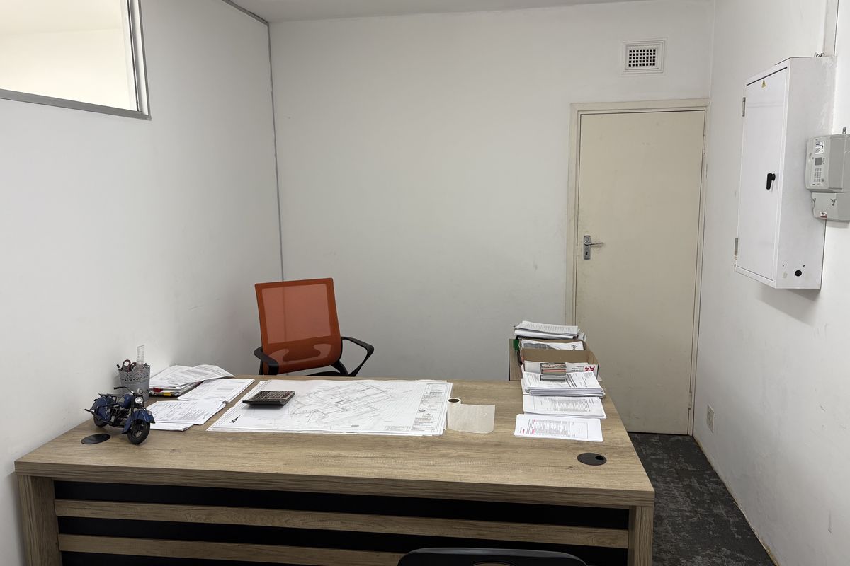 A functional office space featuring a built-in electrical distribution board, ventilation grille, and standard internal door access.
