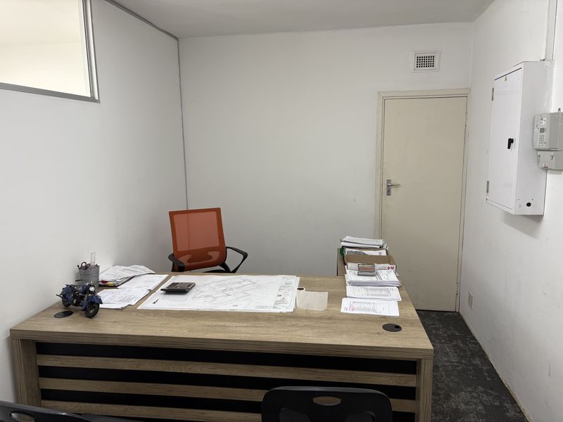 A functional office space featuring a built-in electrical distribution board, ventilation grille, and standard internal door access.