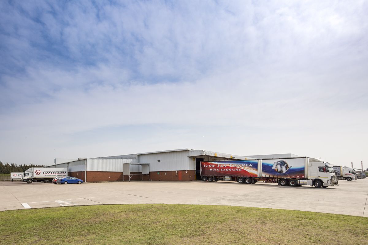 Industrial warehouse facility featuring a large concrete yard, multiple loading bays, and metal cladding exterior, suitable for logistics and distribution operations.
