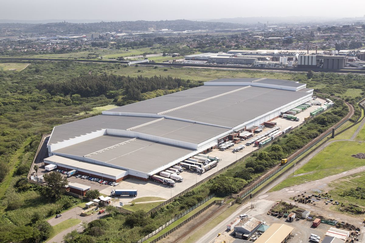 Aerial view of a large-scale industrial warehouse facility featuring extensive loading docks, paved yard space, and secure perimeter fencing.