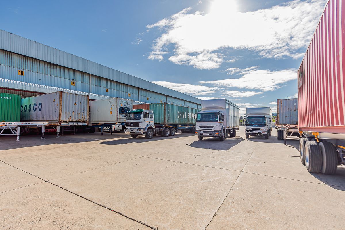 Industrial warehouse facility featuring a large concrete loading yard with multiple loading bays and container storage space.
