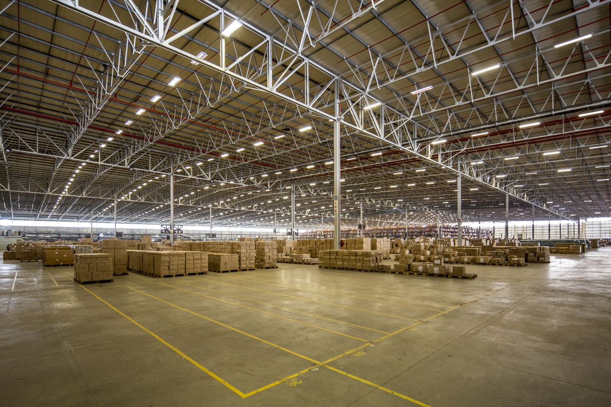 Expansive industrial warehouse space featuring high-clearance steel truss roofing, integrated fire sprinkler systems, and durable concrete flooring with marked loading zones.