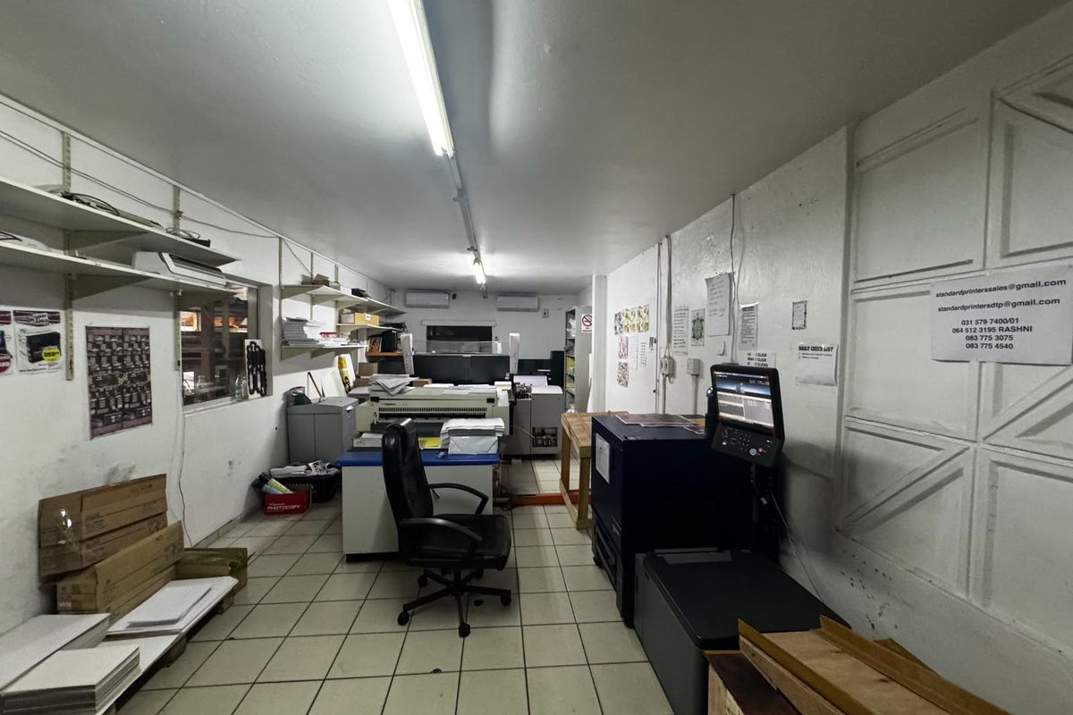 Industrial utility or printing workspace featuring tiled flooring, wall-mounted shelving, and integrated air conditioning units.