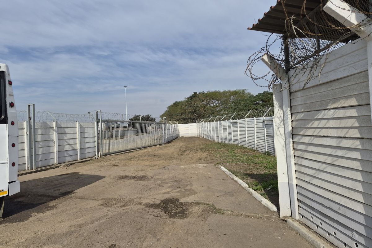 A secure commercial vacant land plot featuring perimeter precast concrete walling with razor wire and a sliding entrance gate.