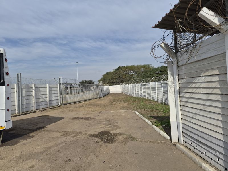 A secure commercial vacant land plot featuring perimeter precast concrete walling with razor wire and a sliding entrance gate.