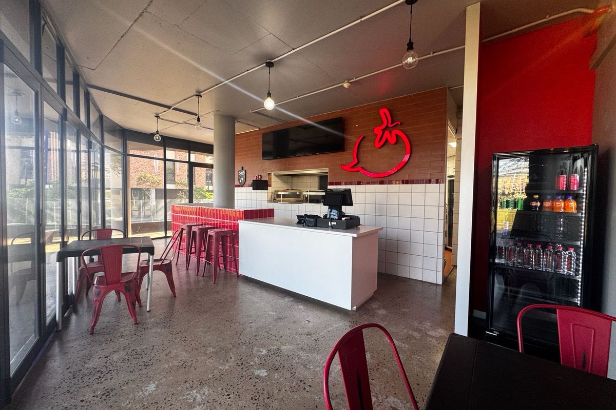 Open-plan retail space featuring polished concrete floors, a tiled service counter, and floor-to-ceiling glass windows providing ample natural light.