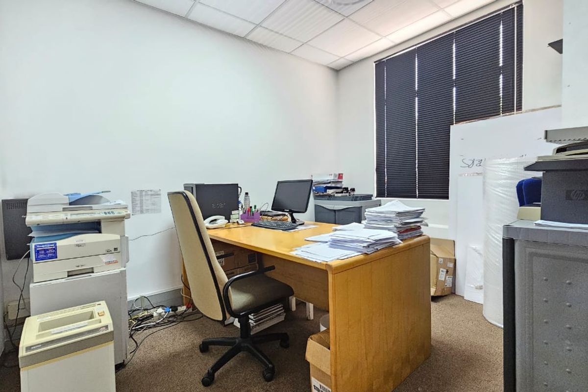 A functional office space featuring carpeted flooring, a suspended ceiling, and window blinds, providing a practical environment for daily business operations.