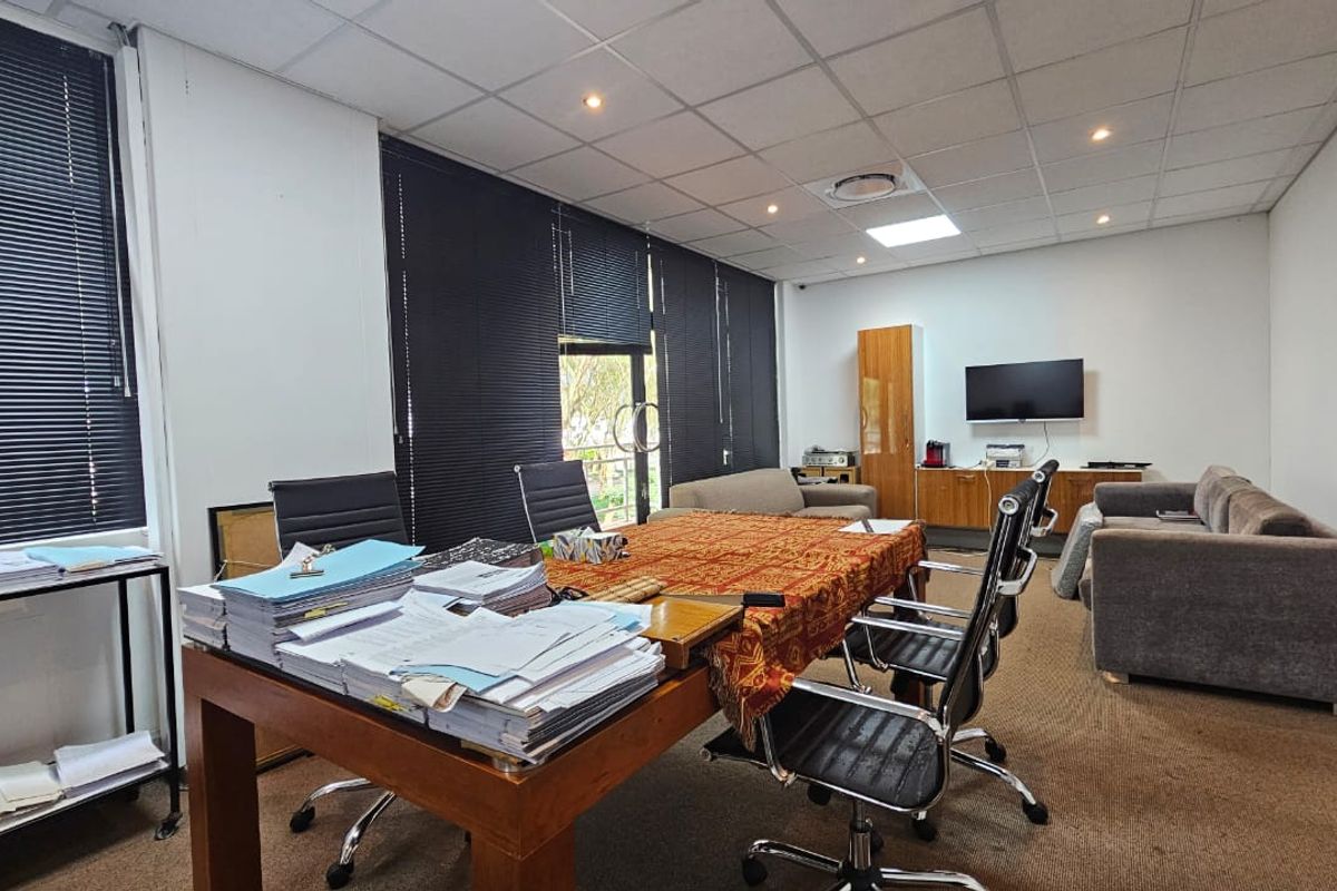 A functional office space featuring a suspended ceiling, recessed lighting, carpeted flooring, and built-in cabinetry, suitable for a professional work environment.