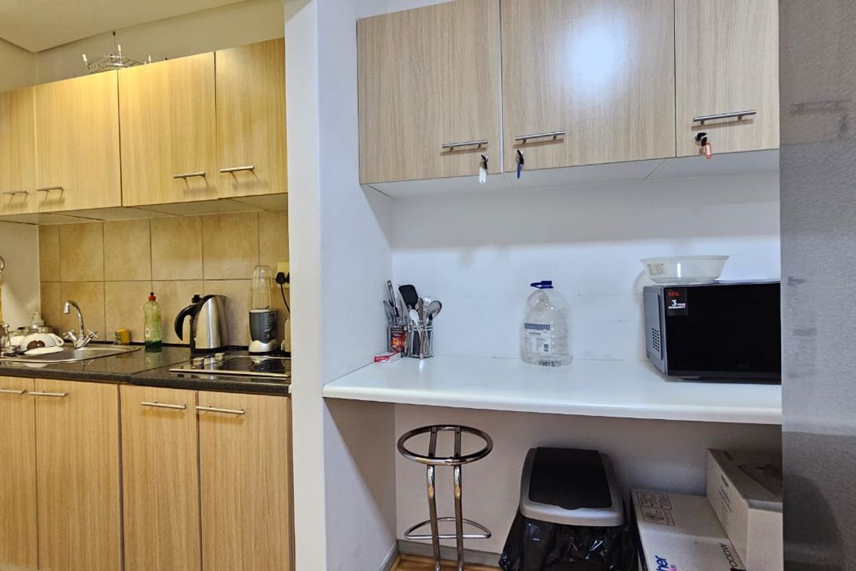 A functional office kitchen area featuring light wood-tone cabinetry, granite countertops, a tiled backsplash, and a dedicated prep or coffee station counter.