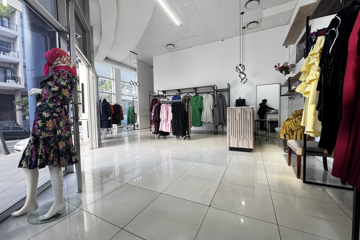 Modern retail space featuring large glass storefront windows, polished tiled flooring, and a suspended ceiling with integrated lighting.