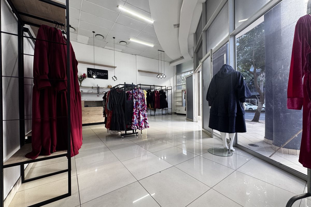 Bright retail boutique space featuring large glass storefront windows, polished tiled flooring, and modern recessed and track lighting throughout the open-plan interior.
