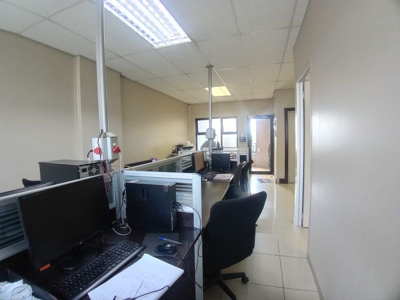 A functional office space featuring tiled flooring, suspended ceiling panels, and integrated electrical conduits, suitable for a professional work environment.