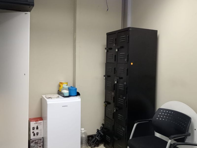 A utility or storage space featuring tiled flooring and a suspended ceiling, currently used for storage with basic infrastructure.