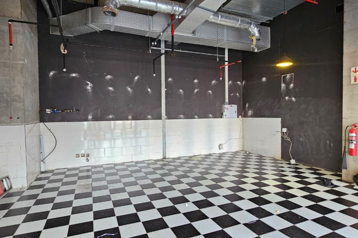 An industrial-style utility space featuring exposed ductwork, a checkered tiled floor, and a functional fire safety system, suitable for various commercial or retail applications.