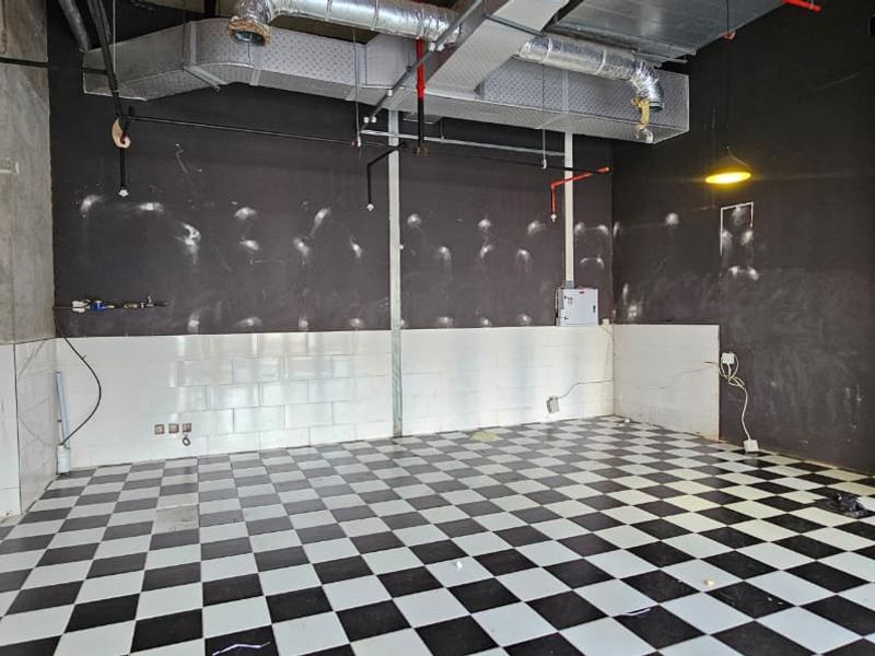 An industrial-style utility space featuring exposed ductwork, a checkered tiled floor, and a functional fire safety system, suitable for various commercial or retail applications.