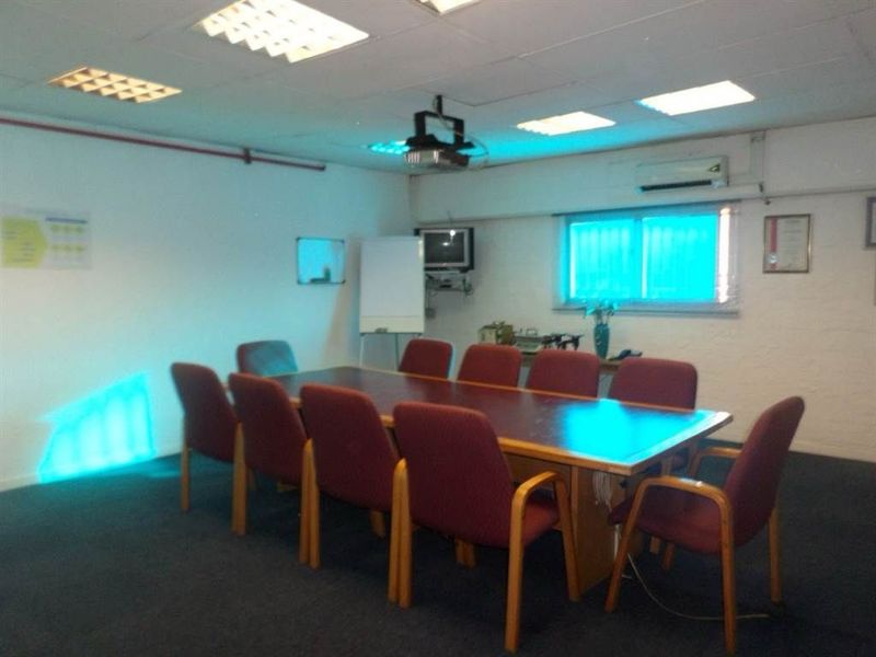 A functional office or boardroom space featuring a suspended ceiling, recessed lighting, and integrated air conditioning, suitable for professional meetings.