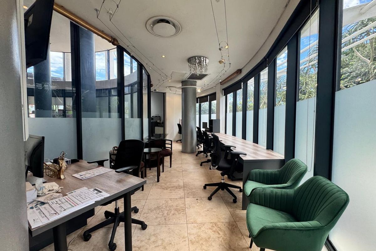 Modern office space featuring extensive floor-to-ceiling windows, tiled flooring, and a bright, open layout suitable for a professional work environment.