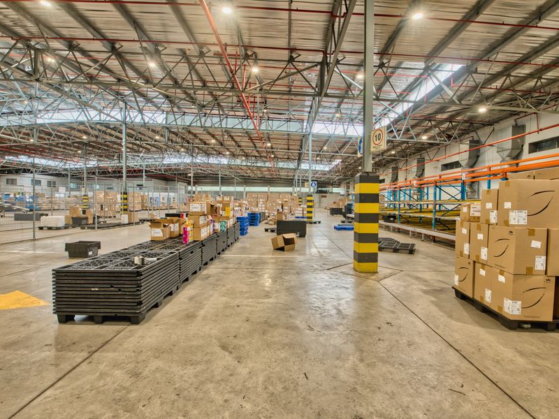 Spacious industrial warehouse facility featuring high exposed steel truss ceilings, durable concrete flooring, and integrated fire sprinkler systems.