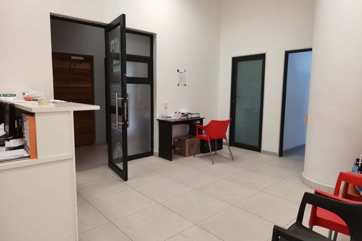 A functional commercial entry and reception area featuring tiled flooring, a built-in reception counter, and multiple access doors.