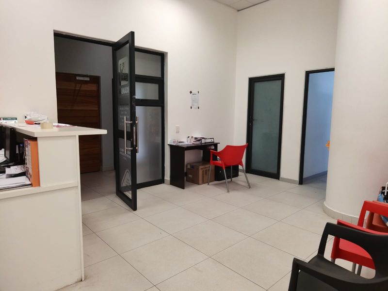A functional commercial entry and reception area featuring tiled flooring, a built-in reception counter, and multiple access doors.
