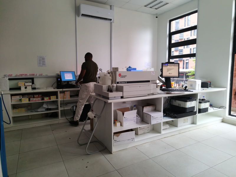 A functional commercial office or laboratory space featuring built-in cabinetry, tiled flooring, and a wall-mounted air conditioning unit.