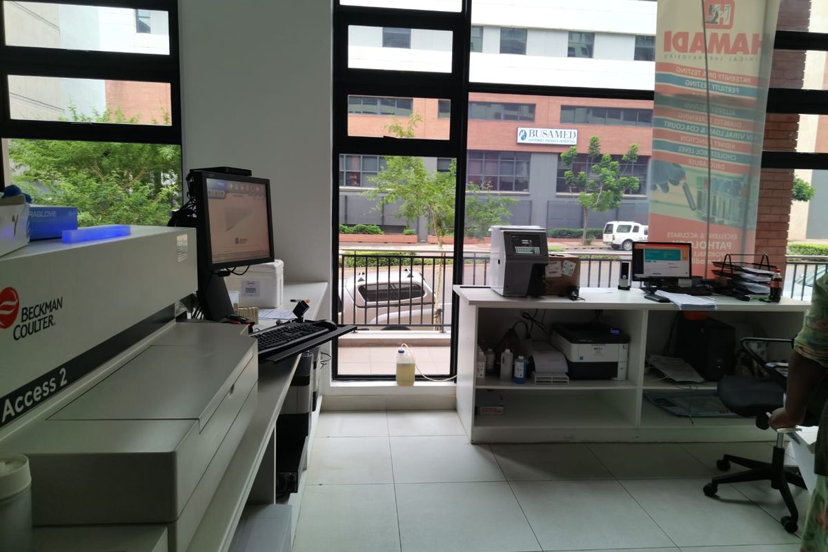 A functional commercial office or laboratory space featuring large windows, built-in cabinetry, and tiled flooring with views of the surrounding street and buildings.
