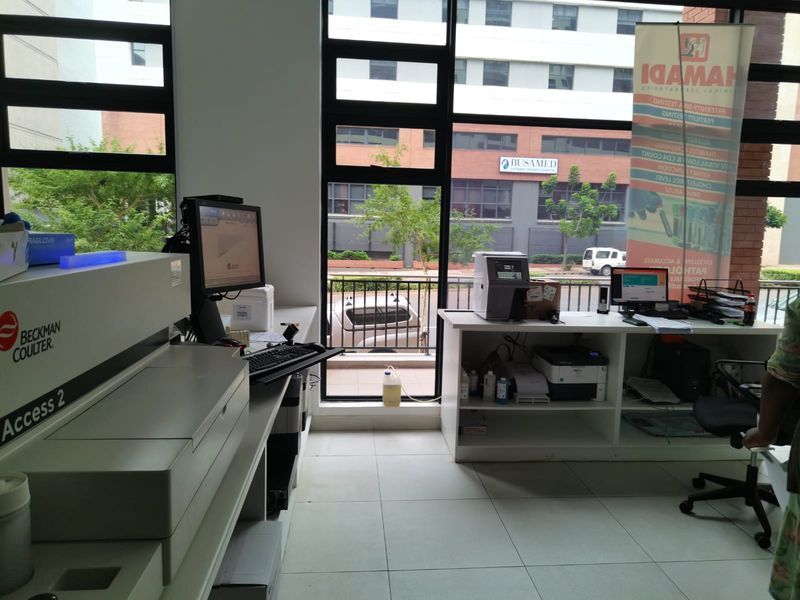A functional commercial office or laboratory space featuring large windows, built-in cabinetry, and tiled flooring with views of the surrounding street and buildings.