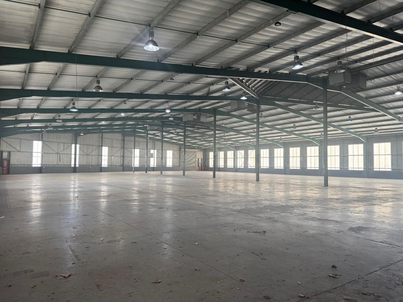 Expansive industrial warehouse space featuring a high-clearance steel portal frame, concrete flooring, and abundant natural light through large perimeter windows.