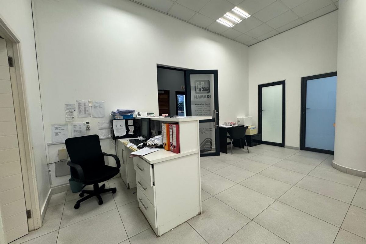 Commercial office space featuring a reception desk, tiled flooring, and suspended ceiling with integrated lighting.