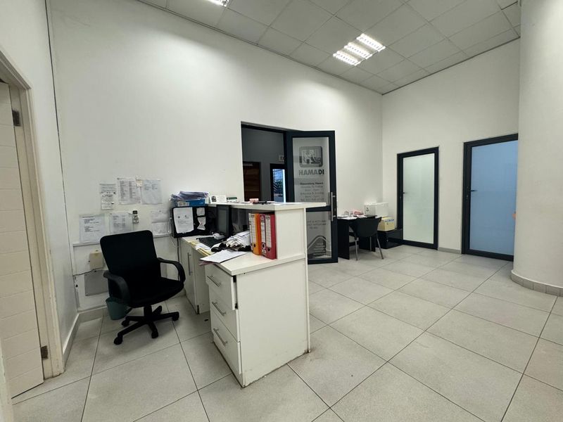 Commercial office space featuring a reception desk, tiled flooring, and suspended ceiling with integrated lighting.
