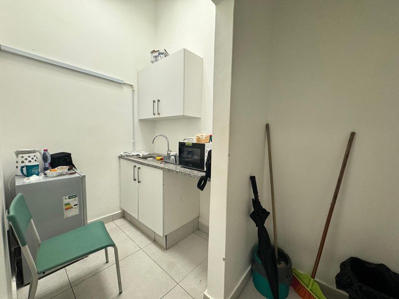 A functional scullery or kitchenette area featuring built-in cabinetry, a stainless steel sink, and granite countertops.