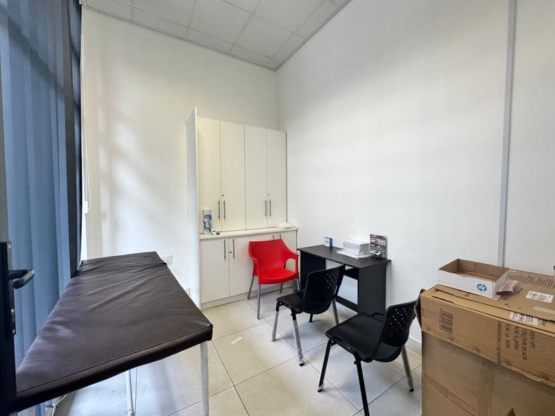 A functional office space featuring built-in storage cabinetry, tiled flooring, and a suspended ceiling, suitable for professional use or a consultation room.