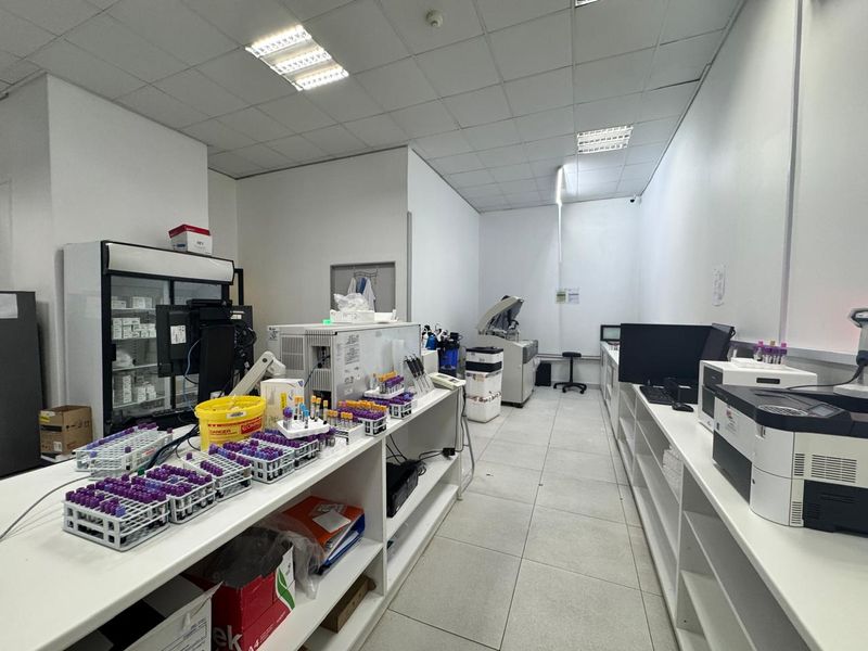 A functional commercial laboratory space featuring built-in cabinetry, tiled flooring, and a suspended ceiling, currently equipped for medical testing and analysis.