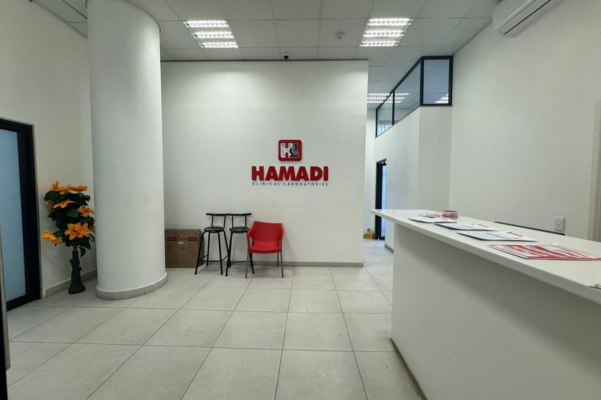 A clean and professional commercial reception area featuring a built-in reception desk, tiled flooring, and a prominent branded wall.