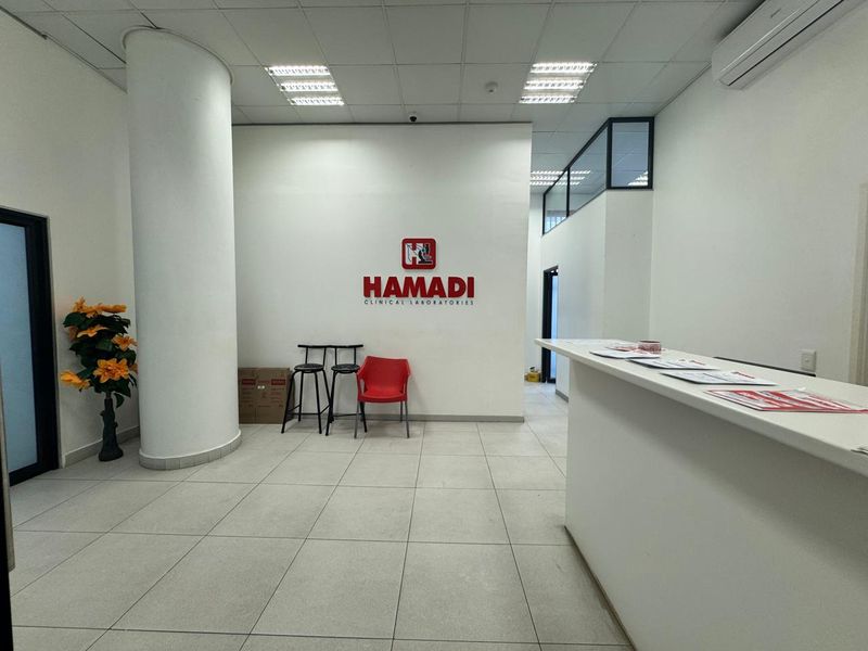 A clean and professional commercial reception area featuring a built-in reception desk, tiled flooring, and a prominent branded wall.