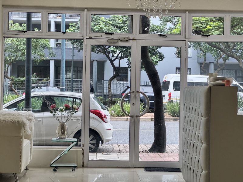 Main entrance area featuring aluminium-framed glass doors and large windows, providing clear visibility to the street and exterior surroundings.