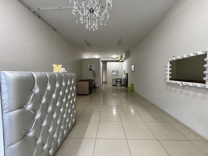 Open-plan retail space featuring neutral walls, tiled flooring, and a prominent vanity mirror, suitable for a salon or boutique layout.