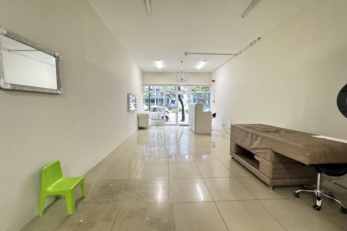 Open plan retail or commercial space featuring tiled flooring, large glass storefront entrance, and surface-mounted lighting fixtures.