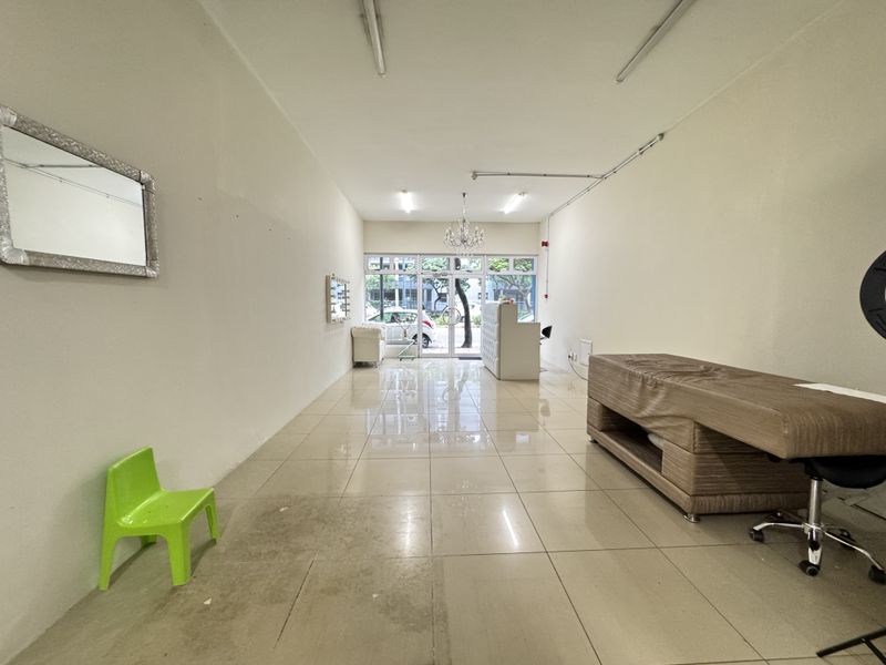 Open plan retail or commercial space featuring tiled flooring, large glass storefront entrance, and surface-mounted lighting fixtures.