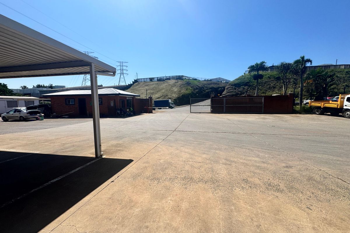 Spacious industrial yard featuring a concrete surface, covered parking area, and secure gated access point.