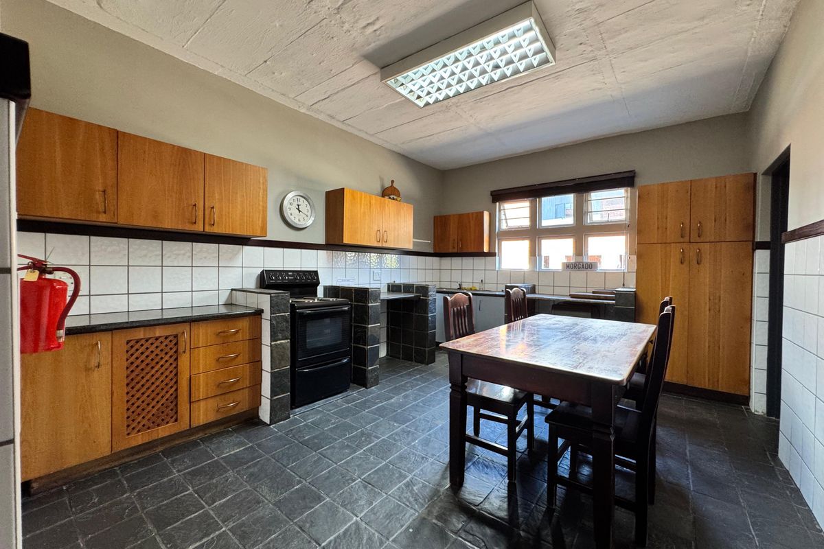 Spacious industrial-style kitchen featuring wooden cabinetry, black granite countertops, tiled flooring, and a functional layout with ample storage and workspace.