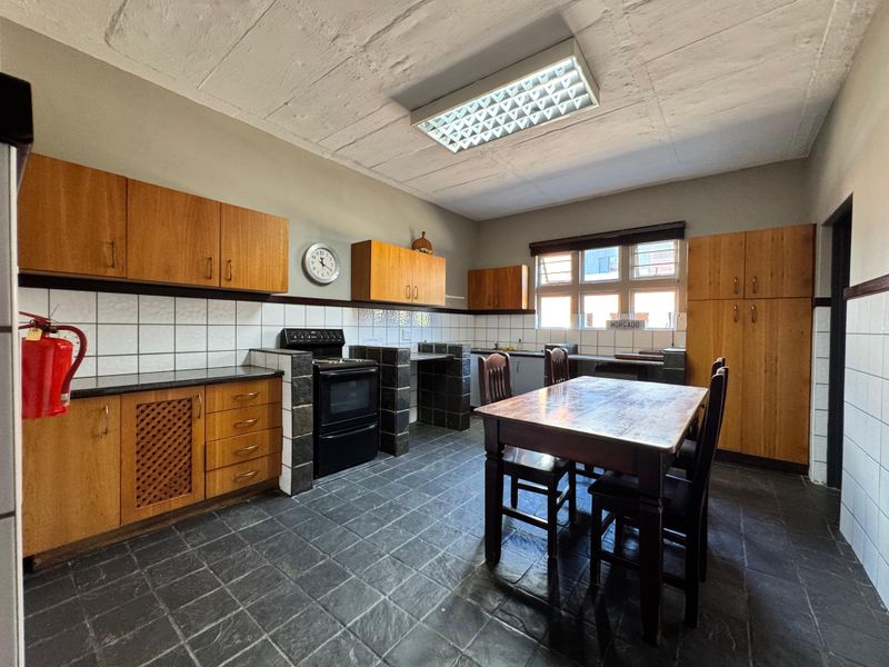Spacious industrial-style kitchen featuring wooden cabinetry, black granite countertops, tiled flooring, and a functional layout with ample storage and workspace.